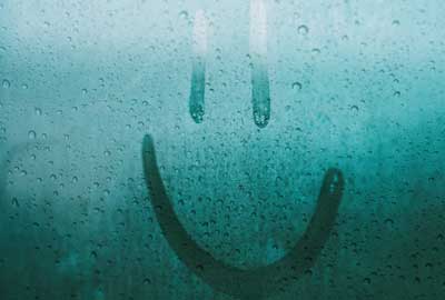 Condensation on a window with a smiley face drawn on it.
